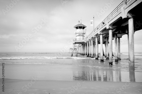 black and white photo of ocean pier with small waves #90094673