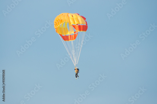 Parachutist in bright yellow-orange parachute parachute