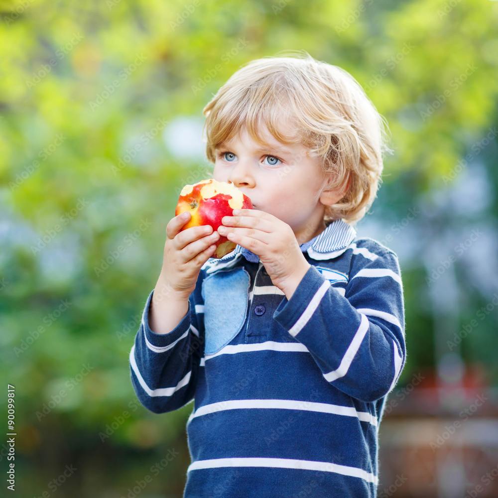 Funny blond kid boy eating healthy apple Funny blond kid boy eating healthy apple