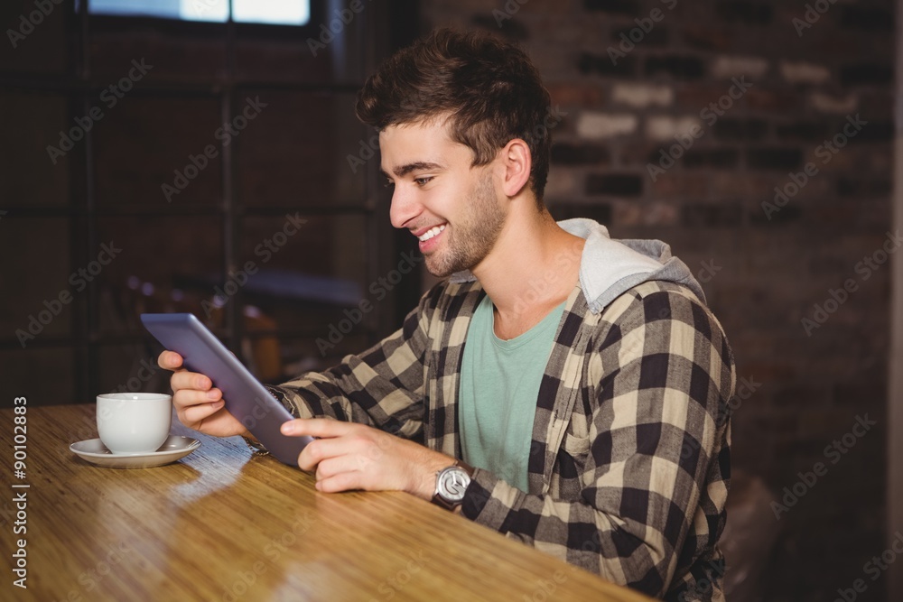 Smiling hipster sitting and using tablet computer Smiling hipster sitting and using tablet computer