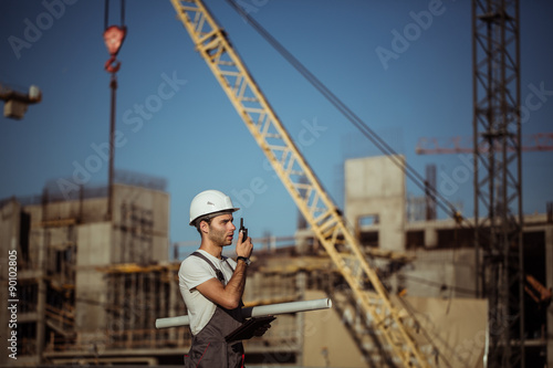 Fotografie Engineer builder using a walkie talkie giving instructions at construction site