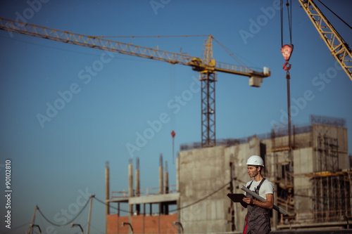 Engineer builder using tablet and walkie talkie, giving instructions at a construction site