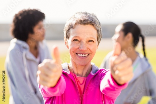 Sporty woman doing thumbs up in front of friends
