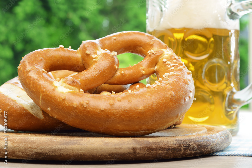 Brezel und Maß Bier im Biergarten zum Oktoberfest in Bayern Brezel und Maß Bier im Biergarten zum Oktoberfest in Bayern