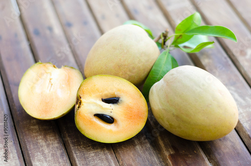 Fresh sweet sapodilla fruit with leaves on wooden background