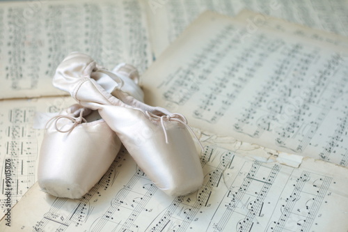 Ballet shoes laying on the old piano musical notes