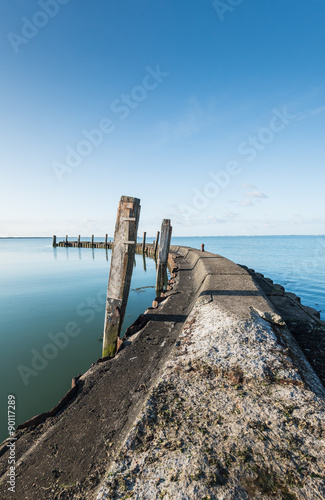 Old jetty with wooden bollards on a windless day