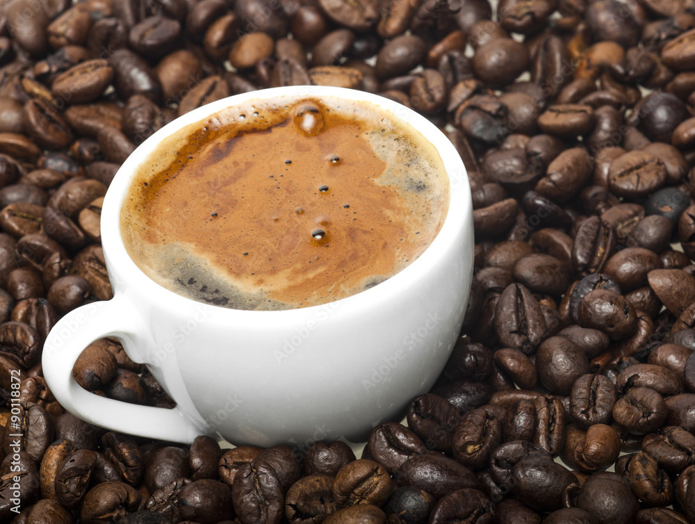 White cup on coffee beans background White cup on coffee beans background