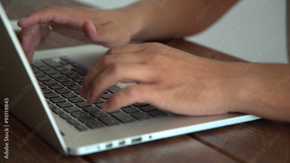 Man working with laptop placed on wooden desk Man working with laptop placed on wooden desk