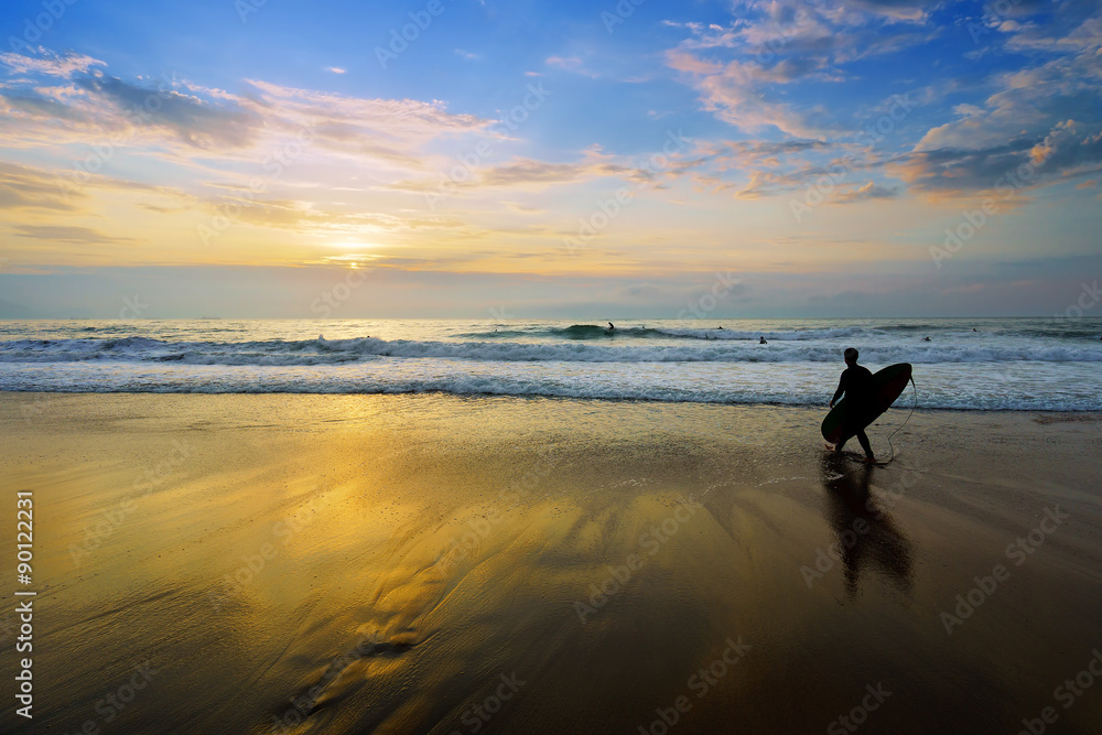 surfer entering water at sunset