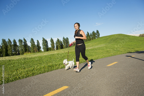 Beautiful young woman jogging with her dog