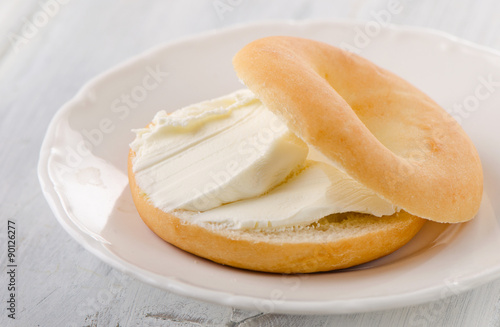 A plate with sliced bagel and cream cheese.