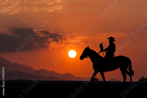 silhouette of Cowboy sitting on his horse at sunset background