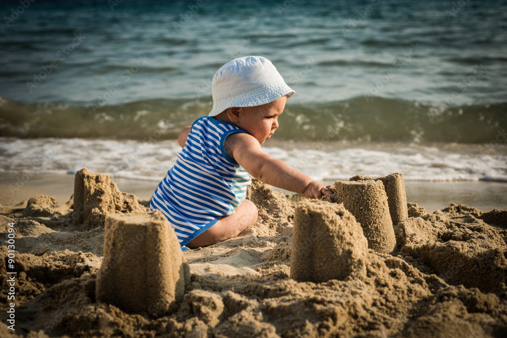  baby boy with a hat sitting on the beach