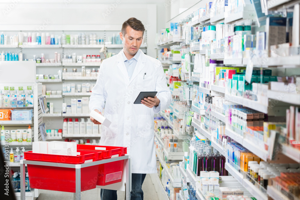 Male Pharmacist Updating Stock In Digital Tablet