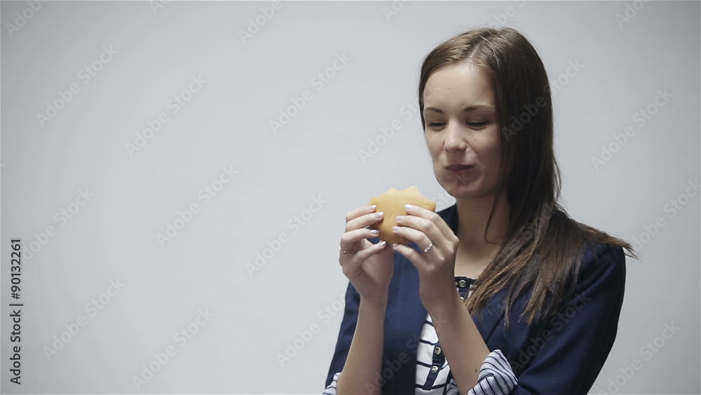 Young woman eating burger at gray background Young woman eating burger at gray background