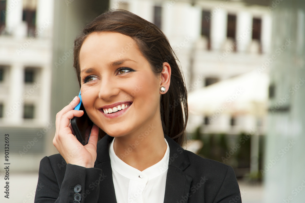 Business woman talking by phone against the glass wall in the ci Business woman talking by phone against the glass wall in the ci
