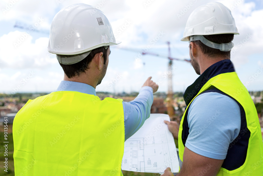 Engineer and worker watching blueprint on construction site Engineer and worker watching blueprint on construction site
