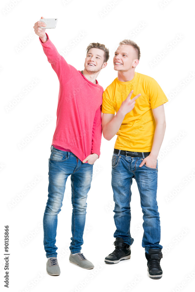 Two happy friends making selfies on isolated background.