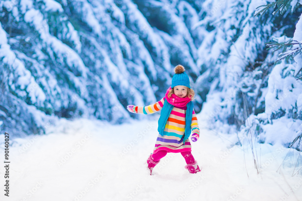 Little girl playing in snowy winter forest