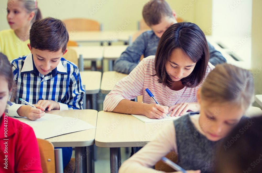 group of school kids writing test in classroom group of school kids writing test in classroom