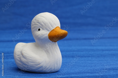 cute white ceramic duck on blue background
