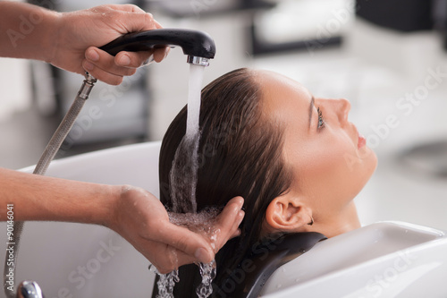 Pretty young woman has her hair washed by hairdresser