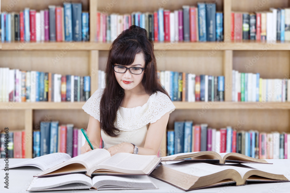 Attactive learner doing school task in library Attactive learner doing school task in library
