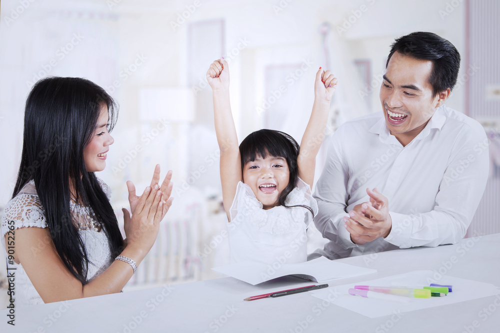 Cheerful kid getting applause from her parents Cheerful kid getting applause from her parents