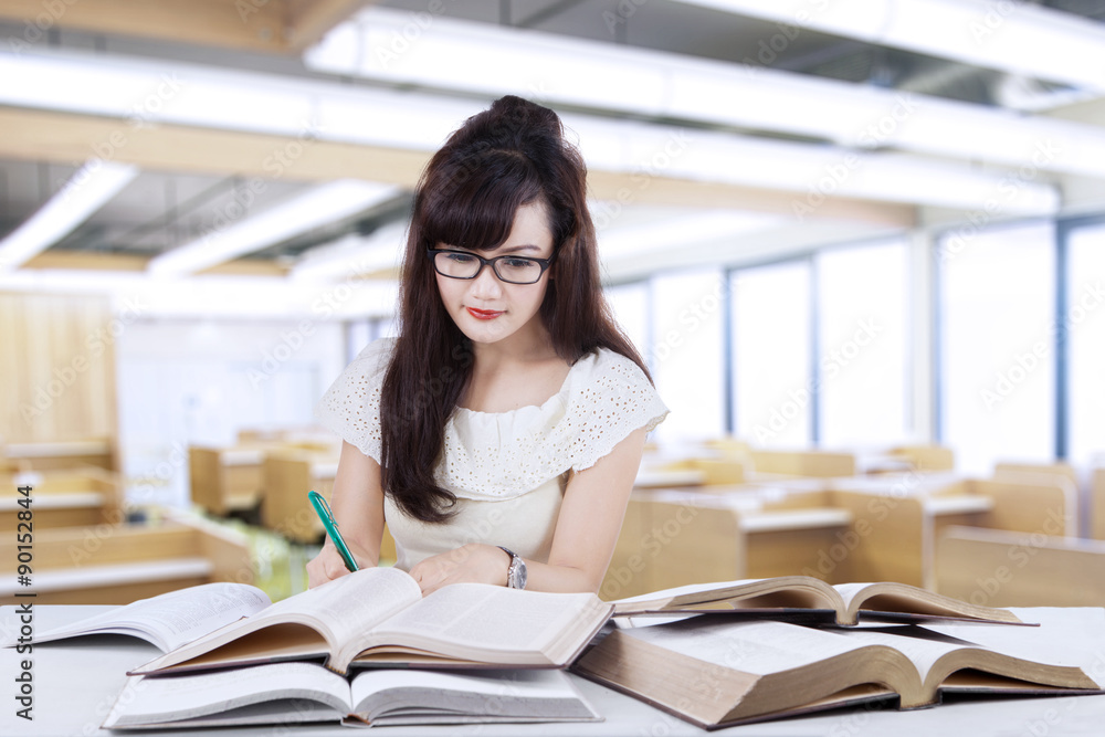 Female learner writing on the book in class Female learner writing on the book in class