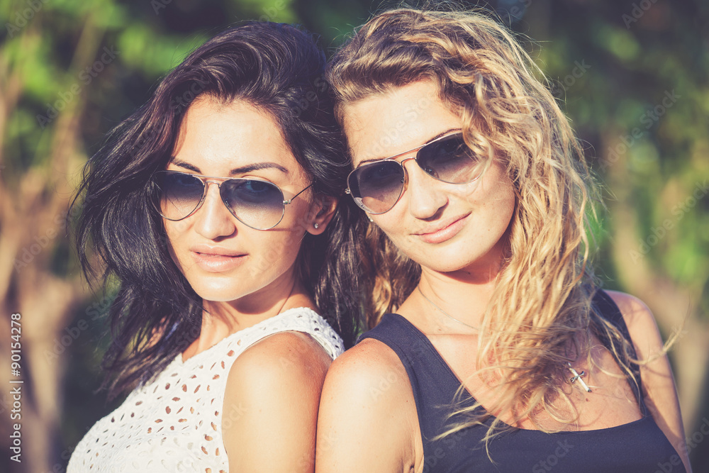 Pretty beautiful brunette and blonde girl friends in sunglasses Pretty beautiful brunette and blonde girl friends in sunglasses