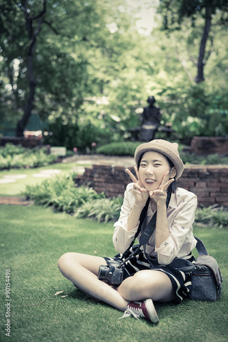 Cute young Asian Thai girl with fashionable clothes is sitting in wilderness garden with natural summer atmosphere in vintage color © 9'63 Creation