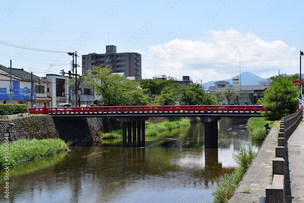 三雪橋（みゆきばし）／山形県の鶴岡市街地をゆっくりと流れる内川。古くから市民の川として親しまれ、「海坂もの」と呼ばれる藤沢周平の小説に登場する「五間川」のモデルとなった川と言われています。この橋から眺める鳥海山、月山、金峰山の３つの山の雪が、とても美しかったことから、明治９年、当時の県知事（三島通庸）が名づけたといわれています。三雪橋の奥に見える山は金峰山です。