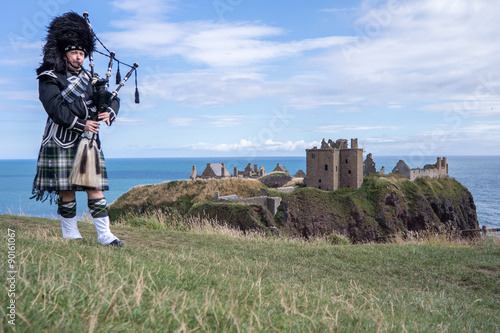 Traditional scottish bagpiper in full dress code at Dunnottar Castle in Stonehaven photo