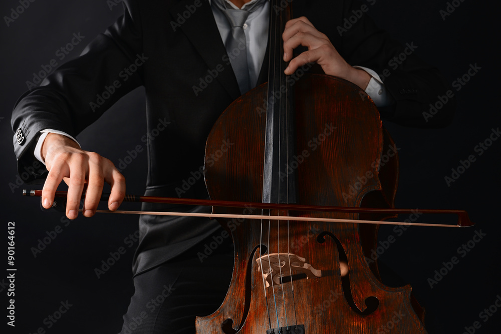 Man playing on cello on dark background Man playing on cello on dark background