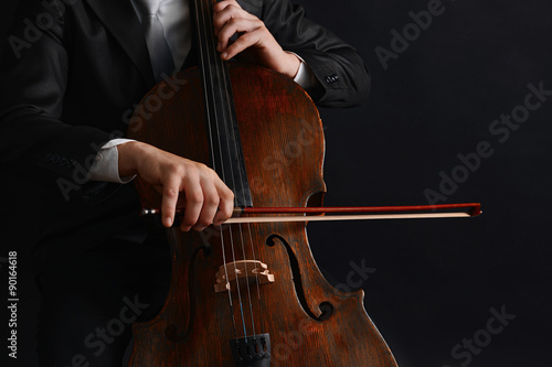 Man playing on cello on dark background