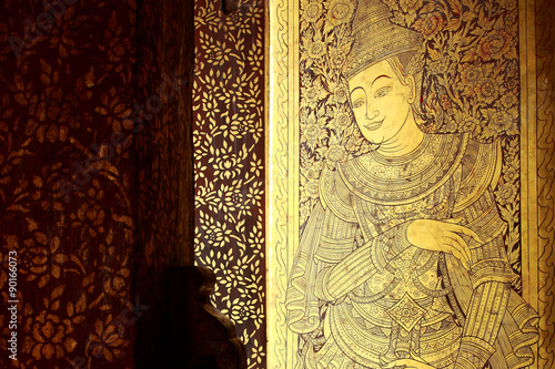 Ancient carved doors covered with lacquer and gold leaves at Wat