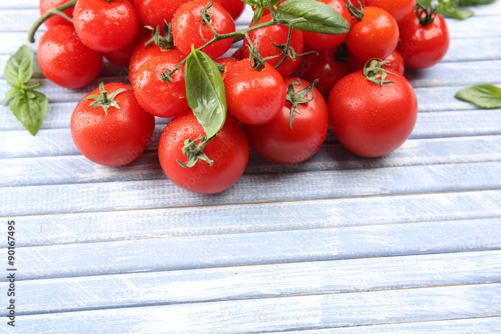 Fresh cherry tomatoes with basil on wooden table close up Fresh cherry tomatoes with basil on wooden table close up