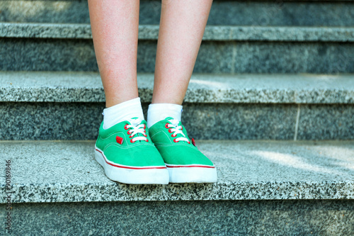 Female feet in green gumshoes on stone stairs