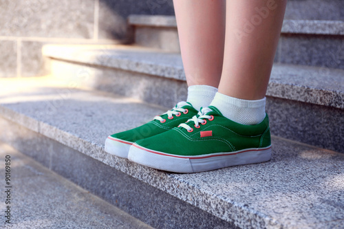 Female feet in green gumshoes on stone stairs