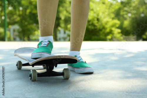 Young skateboarder in gumshoes standing on skate