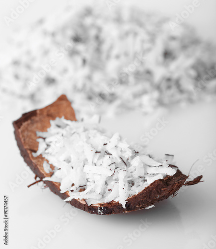 Coconut shavings in coconut shell on white background