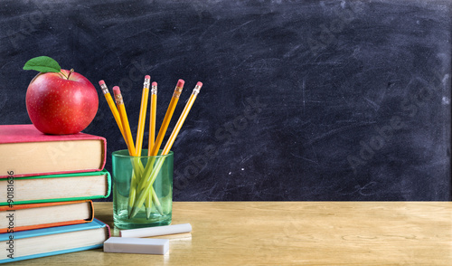 apple on books with pencils and empty blackboard - back to school
