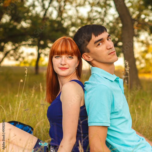beautiful young couple sitting in the field; outdoors