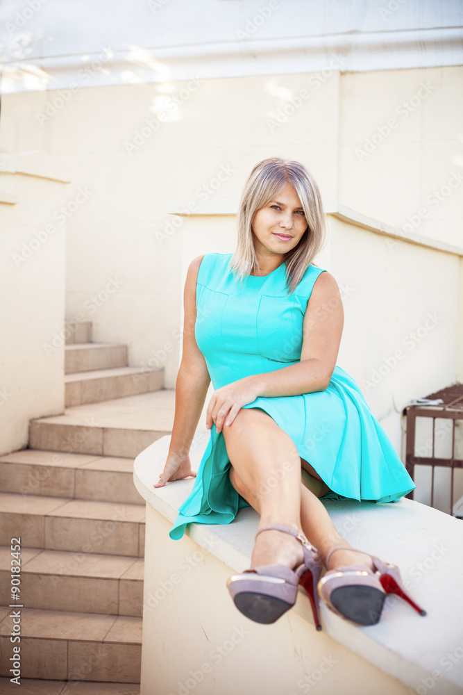 young beautiful girl in a turquoise sundress posing on the steps young beautiful girl in a turquoise sundress posing on the steps
