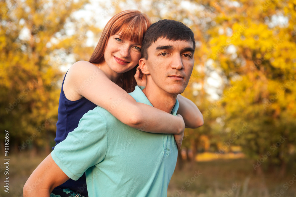 girl sitting on the back of a guy walk in the park outdoors girl sitting on the back of a guy walk in the park outdoors