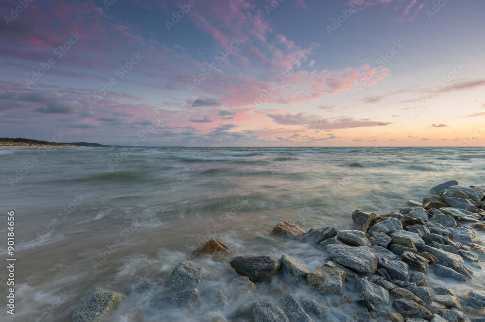 Baltic sea coast at sunset, with granite groyne in Rowy, near Ustka, Poland