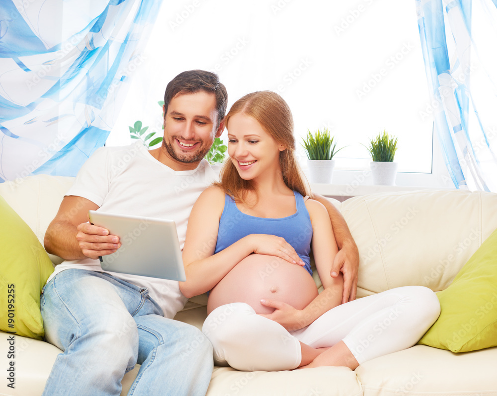 Happy parents waiting malyshayu pregnant mom and dad with tablet Happy parents waiting malyshayu pregnant mom and dad with tablet