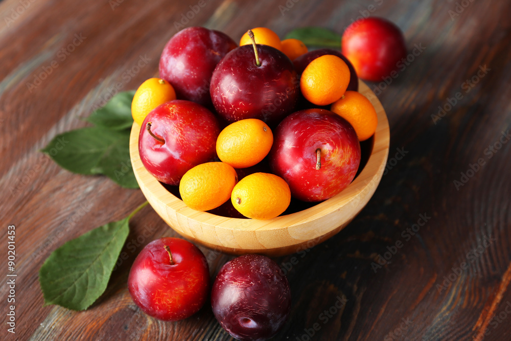 Ripe plums in bowl on wooden background Ripe plums in bowl on wooden background
