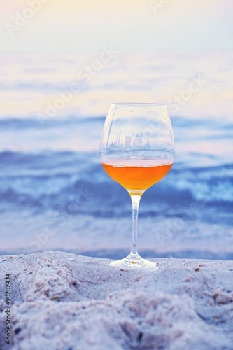Romantic glass of wine sitting on the beach at colorful sunset